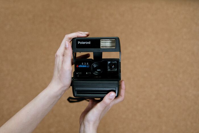 Person Holding A Polaroid Camera In His Hands 