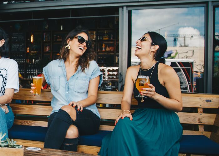 Two woman sitting laughing and drinking beer 