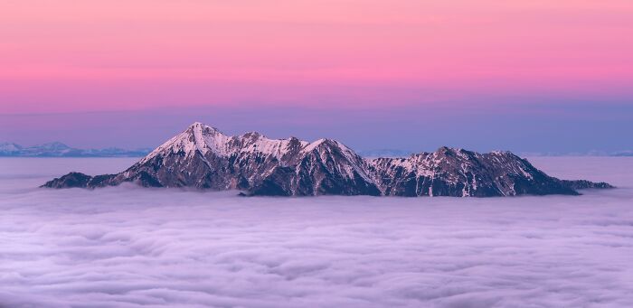 Snowy mountain tops sticking from the clouds 