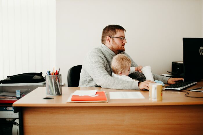 Father works while holding baby