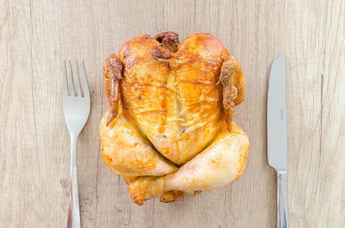 Rotisserie chicken on a table with cutlery 