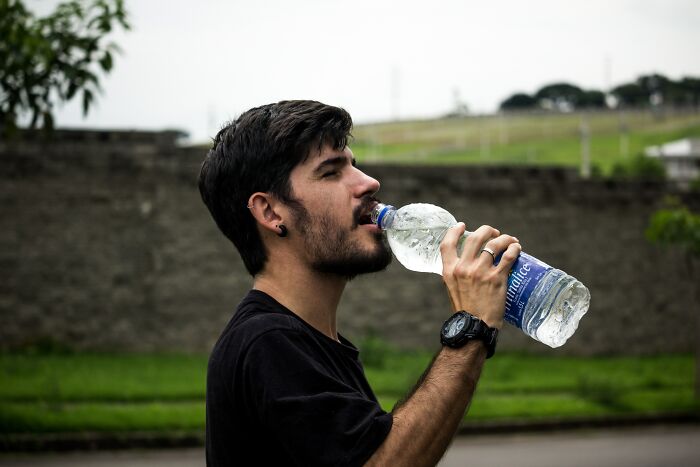 Person drinking water from a plastic bottle 
