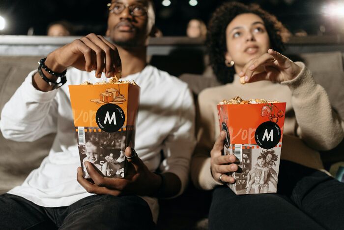 Man and a woman watching a movie and eating popcorn 