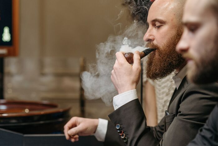 Man with a beard smoking a Pipe tobacco inside 
