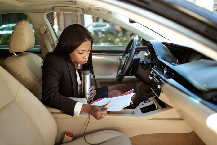 Woman sitting in the car and reading papers 