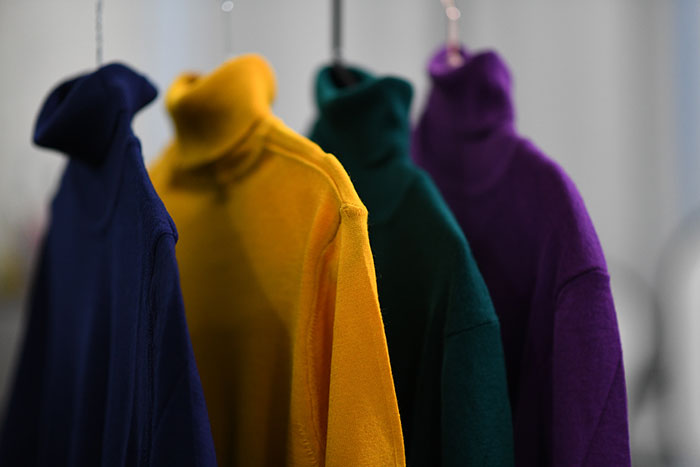 Colourfull sweaters hanging on a hangers