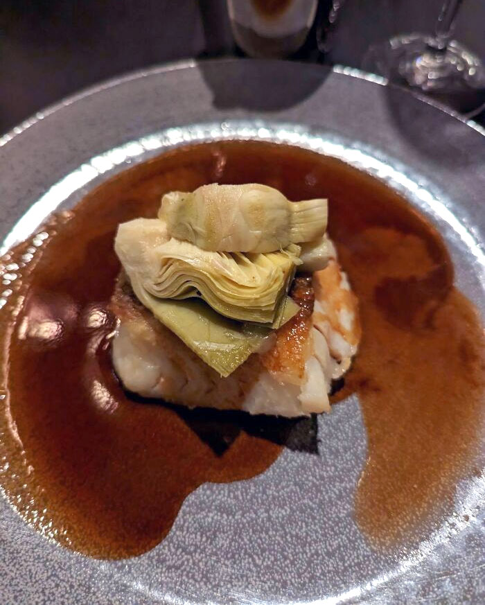 A Tiny Piece Of Fish With Three Pieces Of Canned Artichoke On Top With Brown Sauce. From A Gordon Ramsay Restaurant