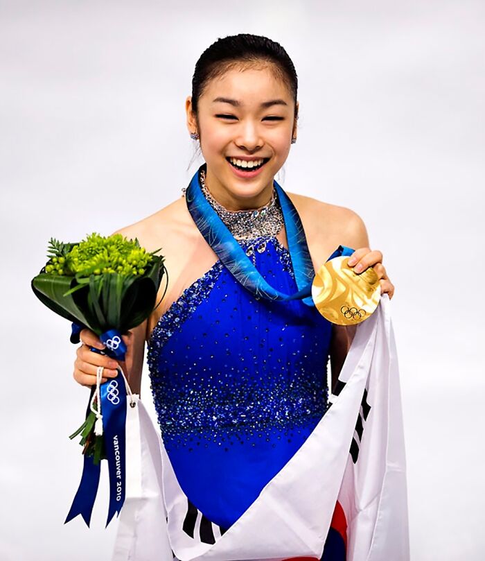 Woman holding a bouquet of flowers and a gold medal in her hands 