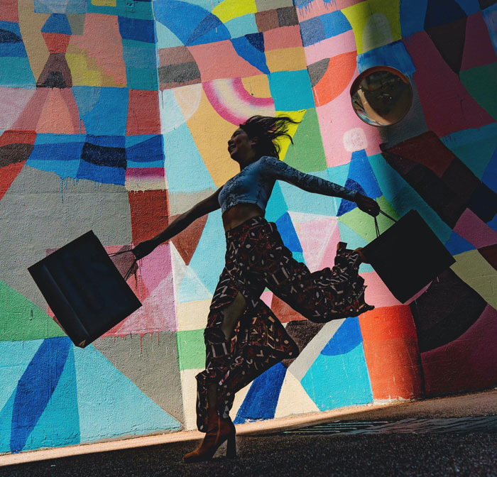 Woman jumping and holding bags