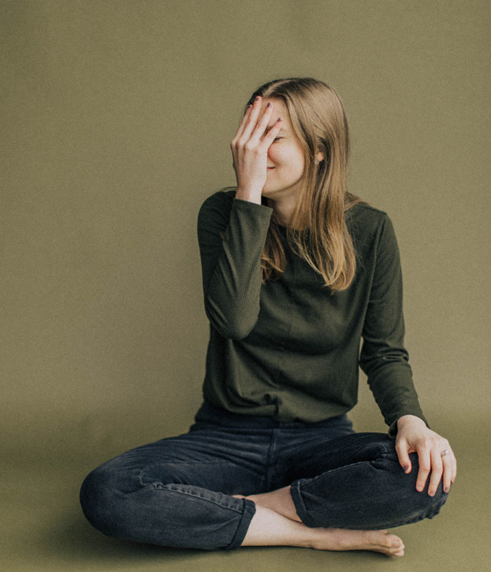 Woman sitting and wearing dark green shirt and blue jeans