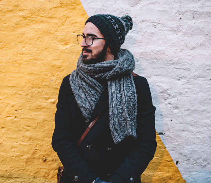 Man standing and wearing jacket, winter hat and scarf