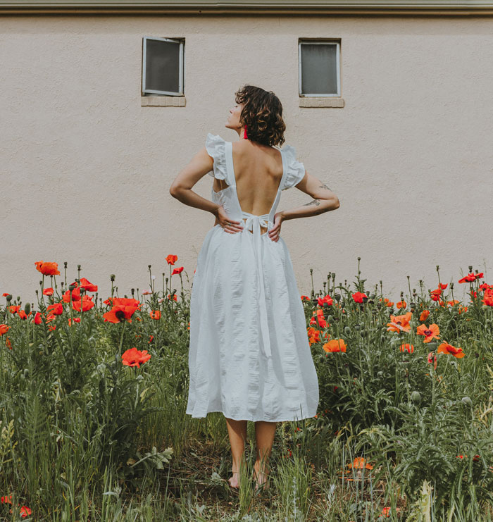 Woman standing in flower field and wearing white dress
