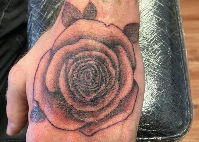 Tattoo design of a rose on a hand, often seen as lacking creativity according to online opinions.