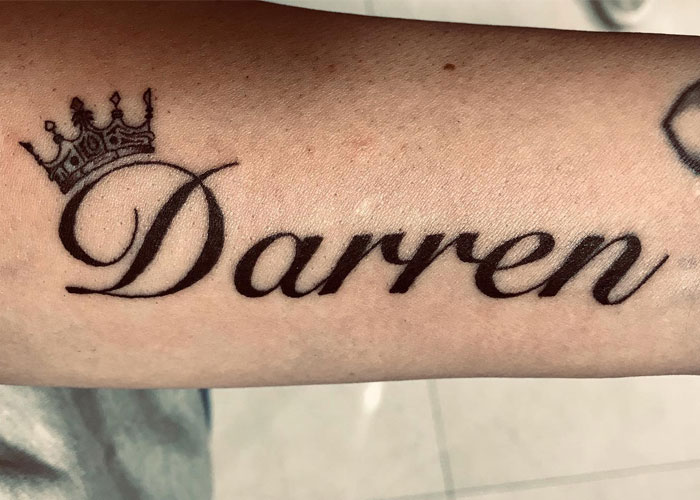 Tattoo design with name and crown on forearm, labeled as lacking creativity in online discussions.