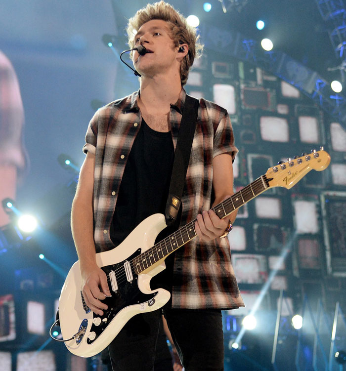 Niall Horan with a guitar singing on the stage 