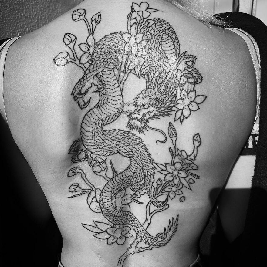 dragon tattoo on a womans back with floral designs