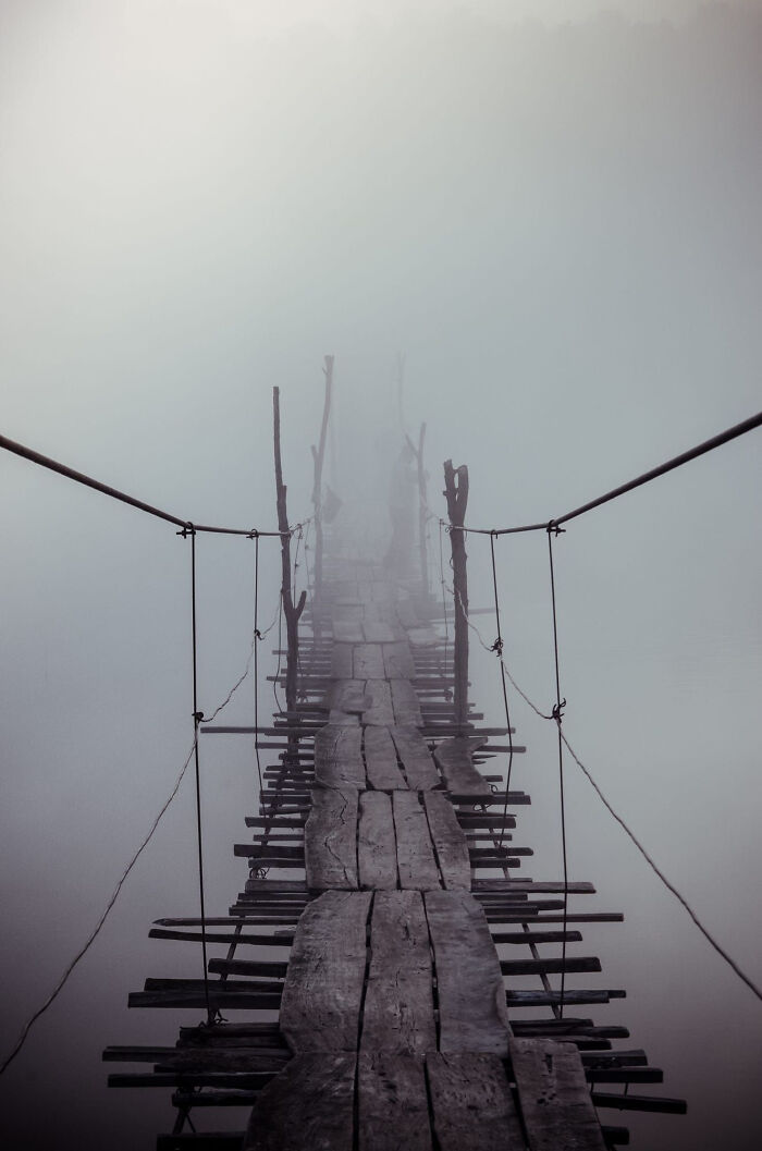 A Rickety Old Foot Bridge Leading Into The Misty Distance