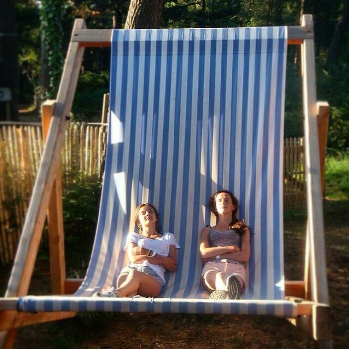 Two women lying in the giant beach chair and sun tanning