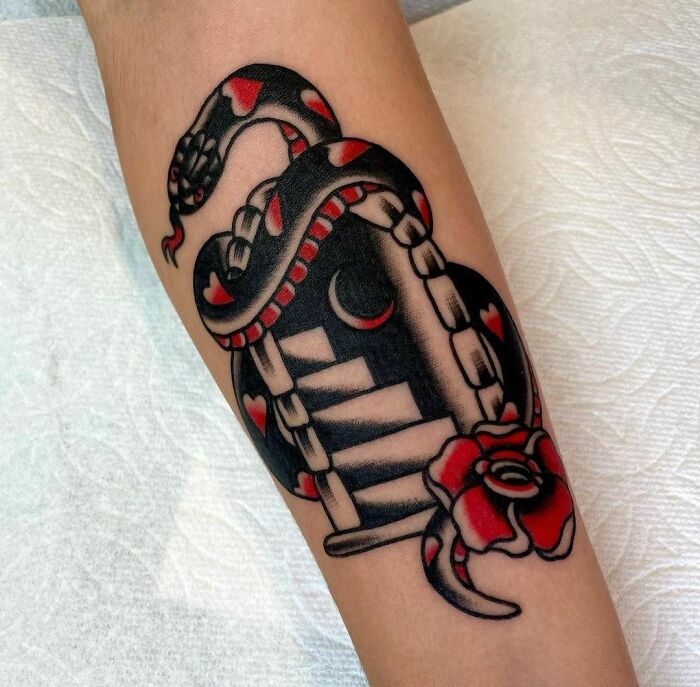 American traditional tattoo with a snake and red rose on arm.