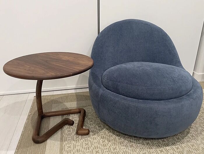 Blue puff chair next to a wooden table with legs crossed 