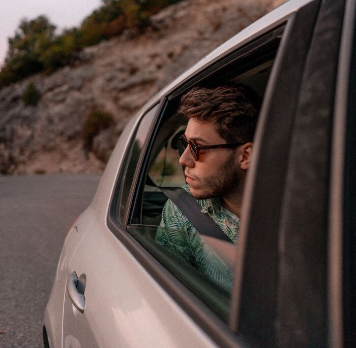 Person wearing sunglasses looking through the car's window 