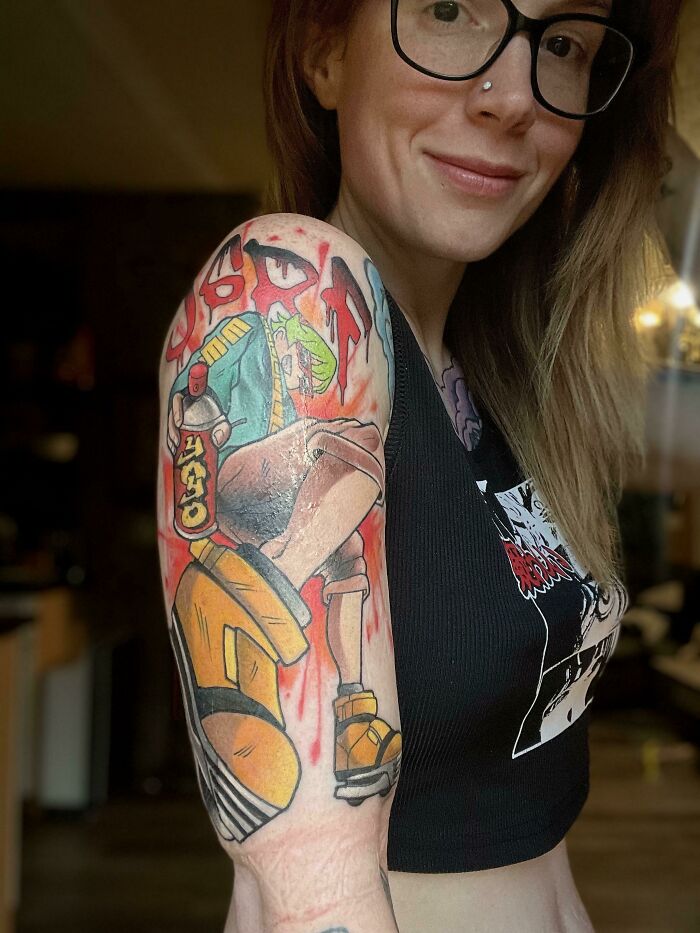 Person with a colorful pop culture tattoo on their arm, featuring vibrant characters from a popular animated series.