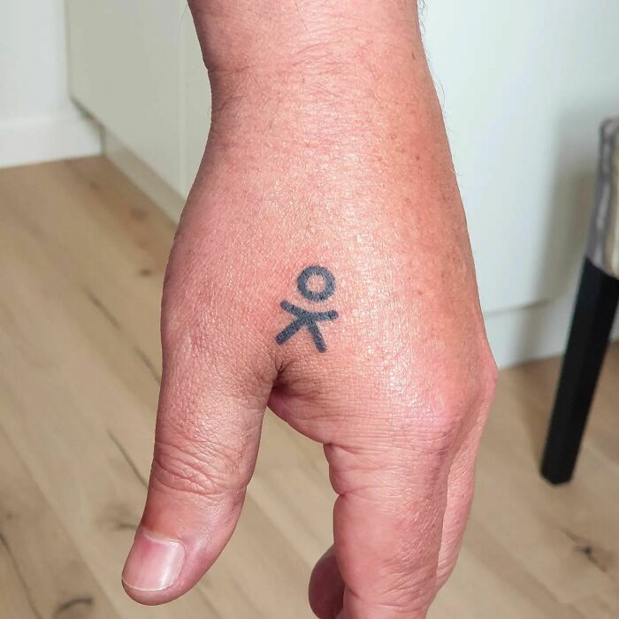 Black small symbol like a human body tattoo on hand