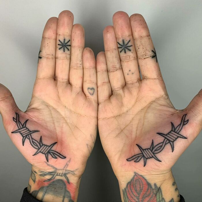 Black barbed wire tattoo on palm and geometric stars tattoo on fingers