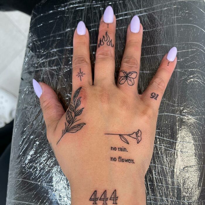 Many different small black linear tattoos on hand