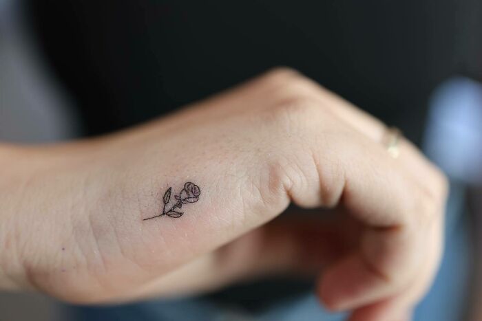 Black small rose tattoo on hand