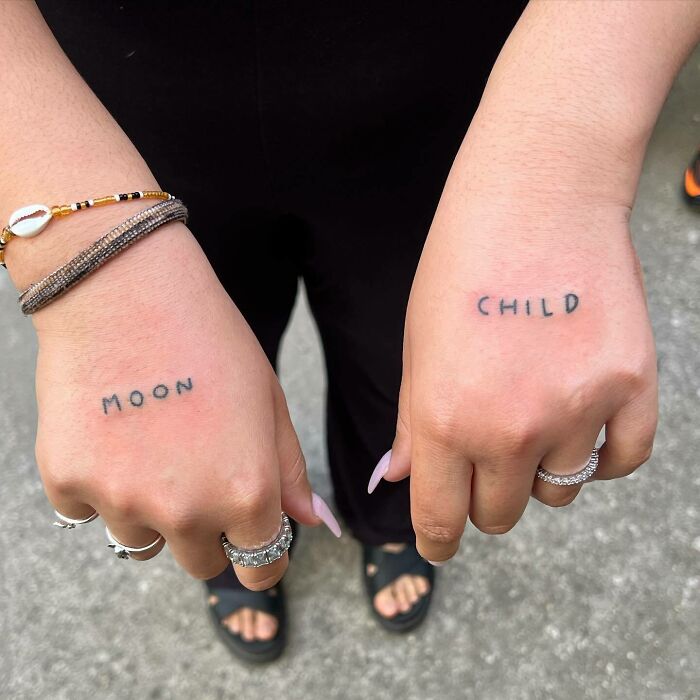 Lettering ‘Moon’ and ‘Child’ tattoos on hands