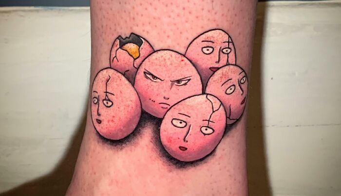 Pop culture tattoo of cartoon-style c*****d eggs with various facial expressions on a person's skin.