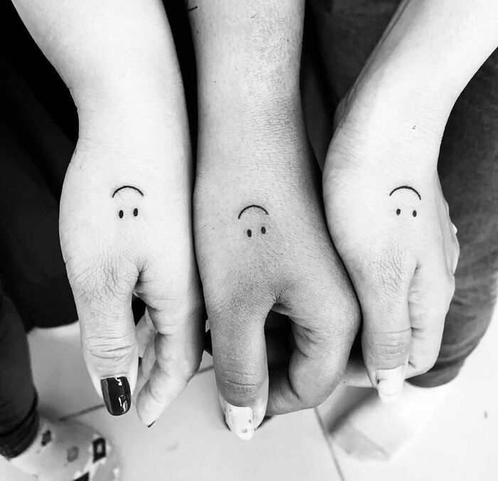 Smiley tattoo on three person's hands