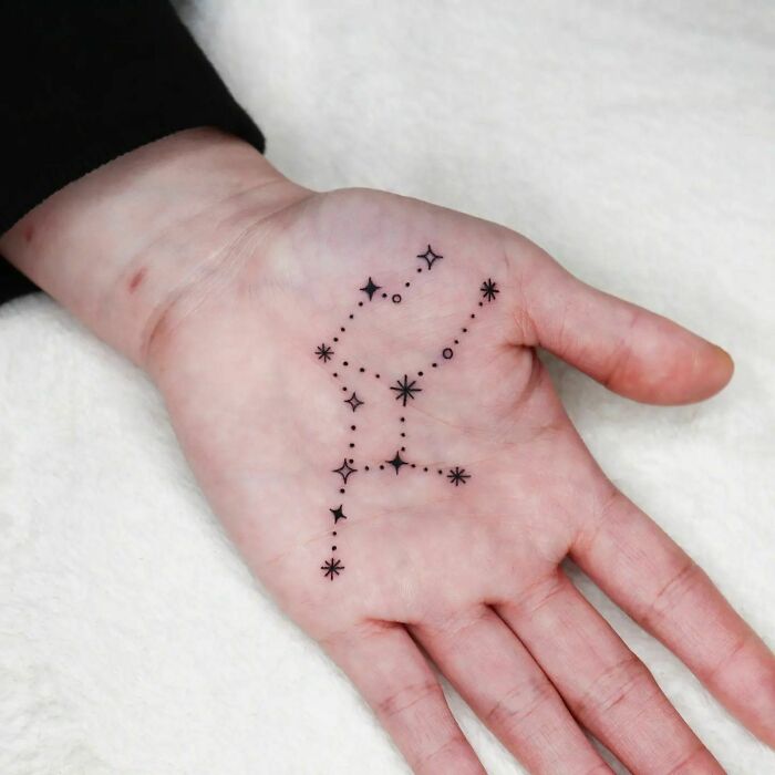 Black constellation tattoo on hand palm