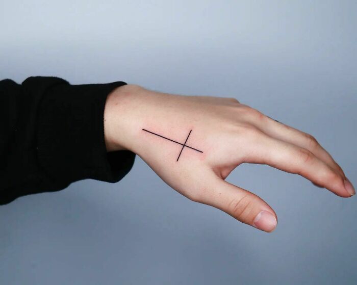 Black minimal cross tattoo on hand