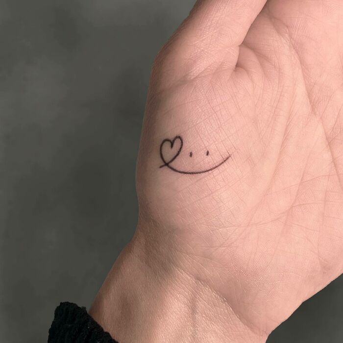 Minimal smile with heart tattoo on palm