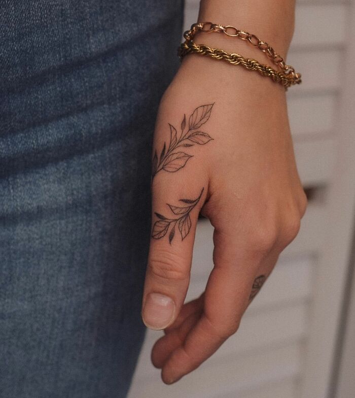 Vines tattoo wrapping around thumb and hand