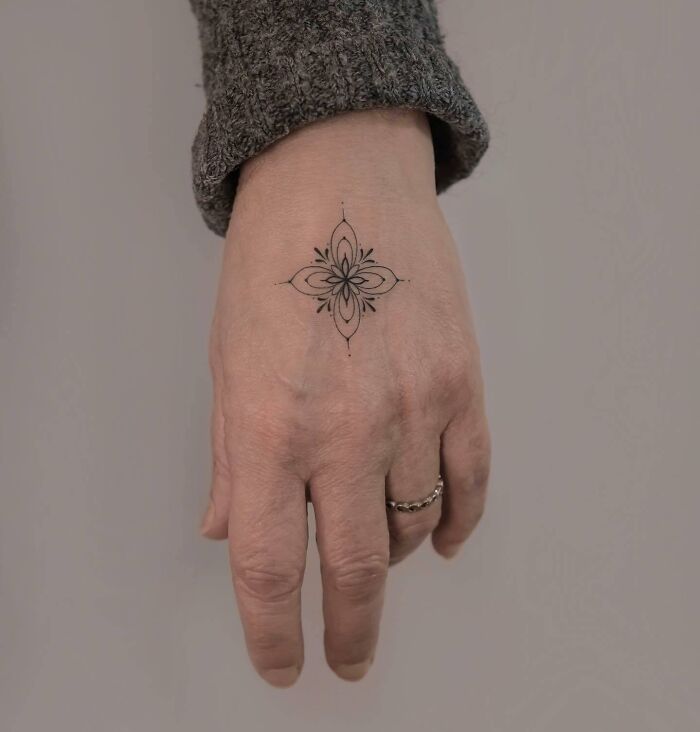 Delicate black ornamental flower tattoo on hand