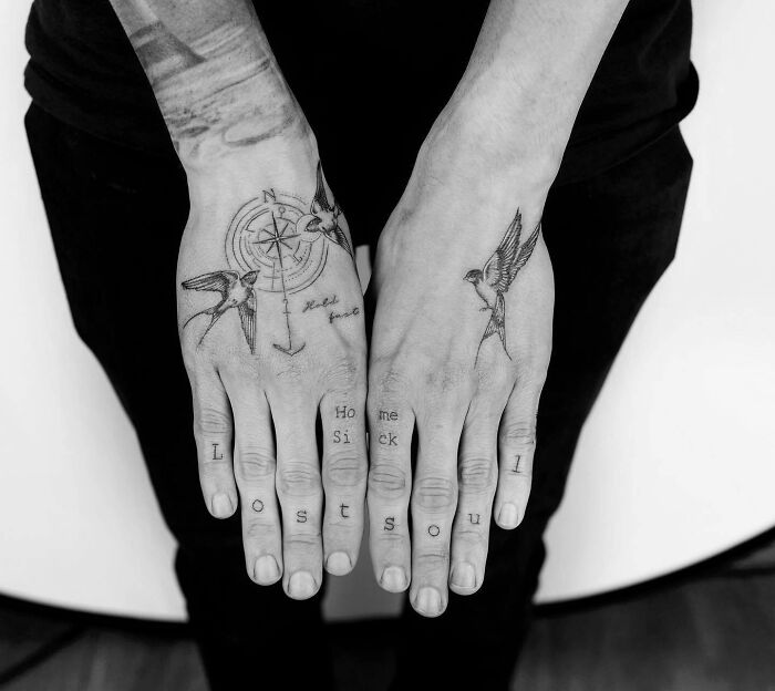 Hand tattoos with swallows, compass, and letters