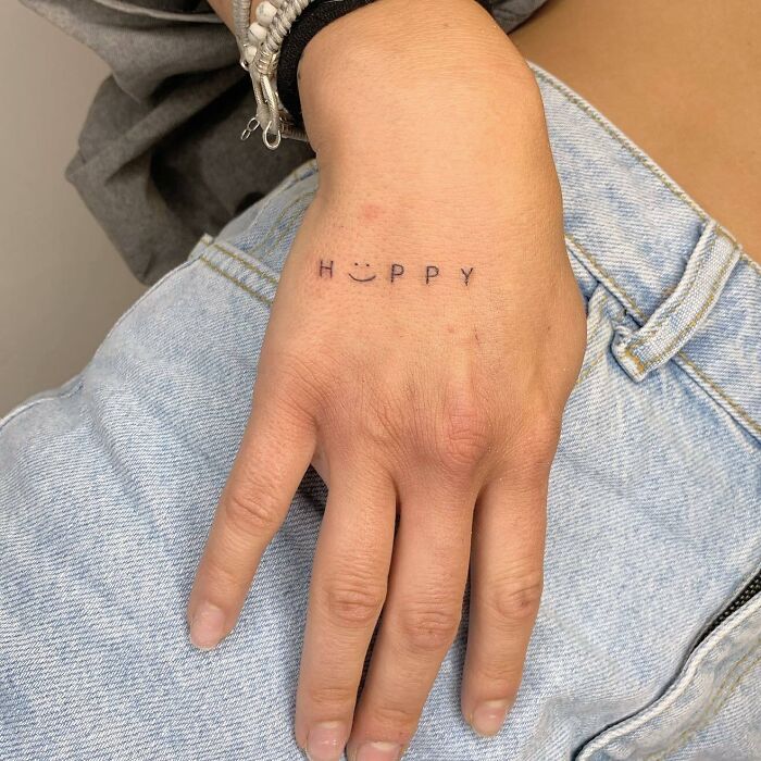 Lettering ‘Happy’ tattoo with smiley face instead of a letter