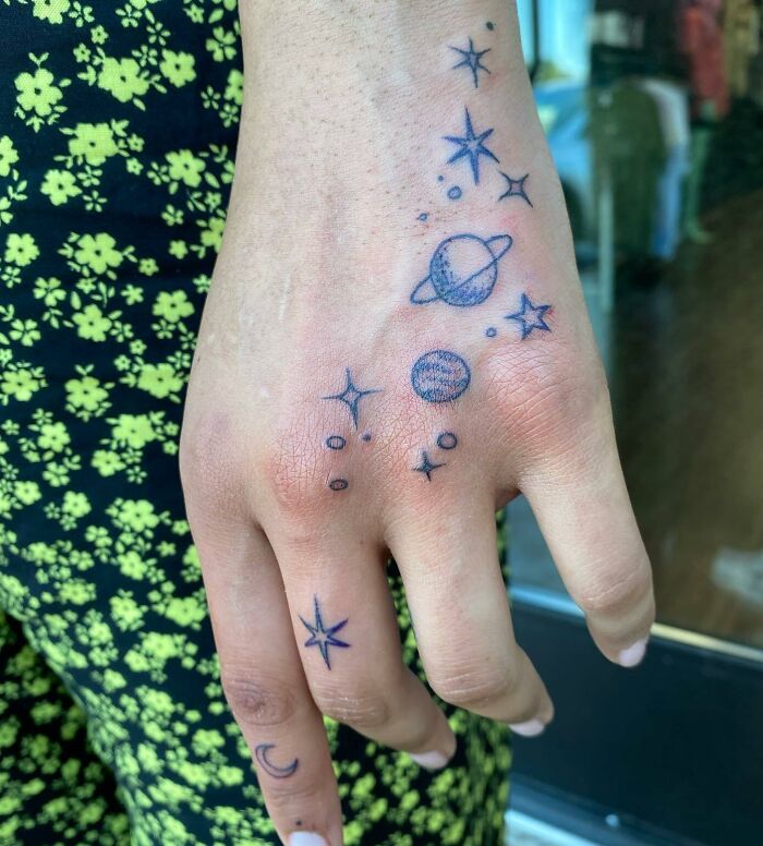 Blue planets and stars tattoos on the hand