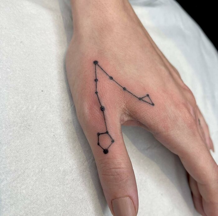 Black hand poked Pisces constellation tattoo on hand