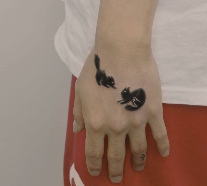 Two black cats tattoo on the hand