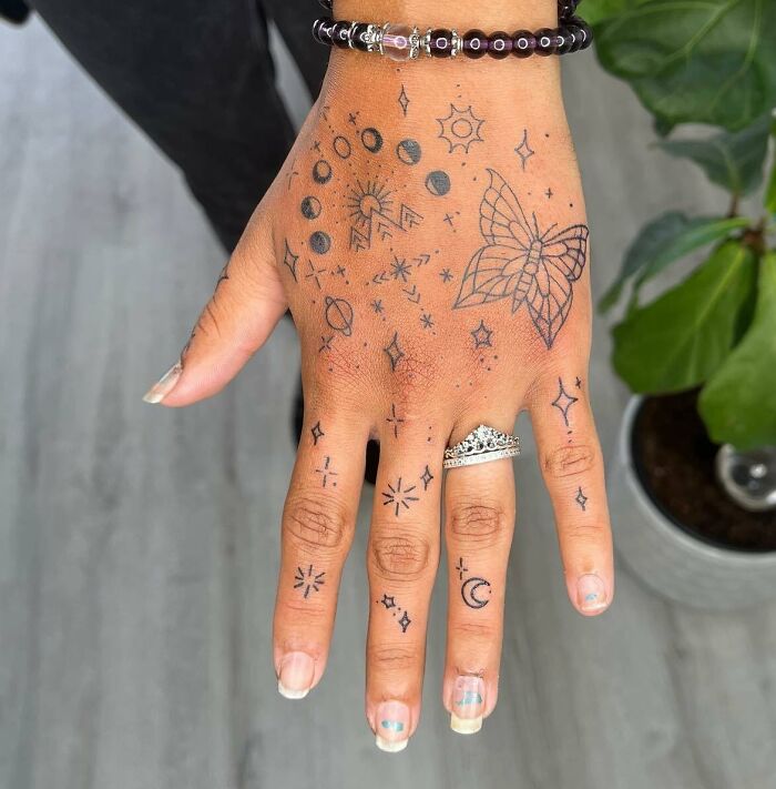 Many small hand tattoos with butterfly, mountains, moon phases and stars