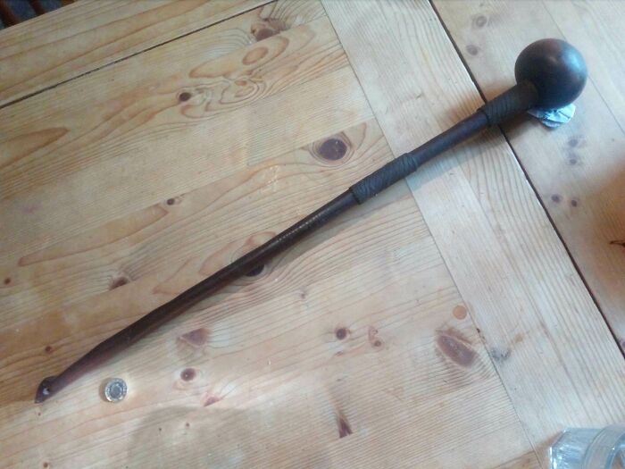 Wooden Stick. Made Of Dark Wood With Wrapped String Detail, Roughly 2 Feet Long, With Big Heavy Lump At One End, And A Small Hole The Other End. Too Short To Be A Walking Stick