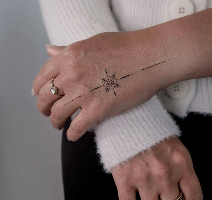 Black ornamental small flower tattoo on hand