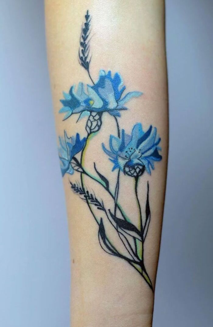 Blue flower tattoo on forearm, showcasing elegance and beauty through intricate design and vibrant color.