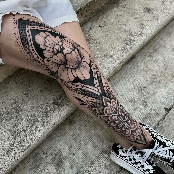 Intricate knee tattoo with geometric patterns and a floral design, creating a bold artistic statement.