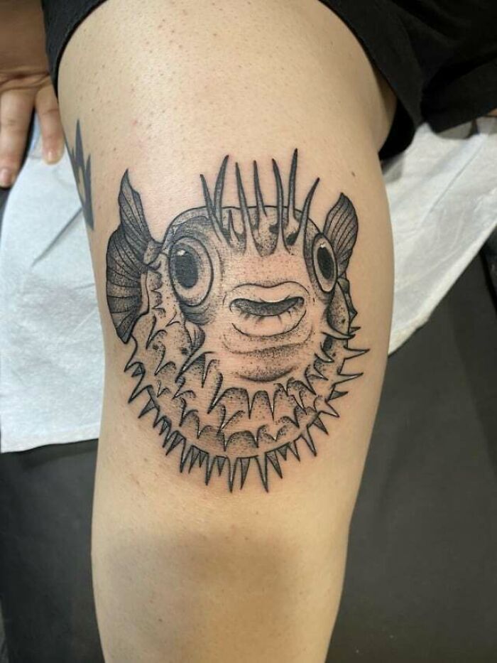 Pufferfish knee tattoo design in black ink on skin.