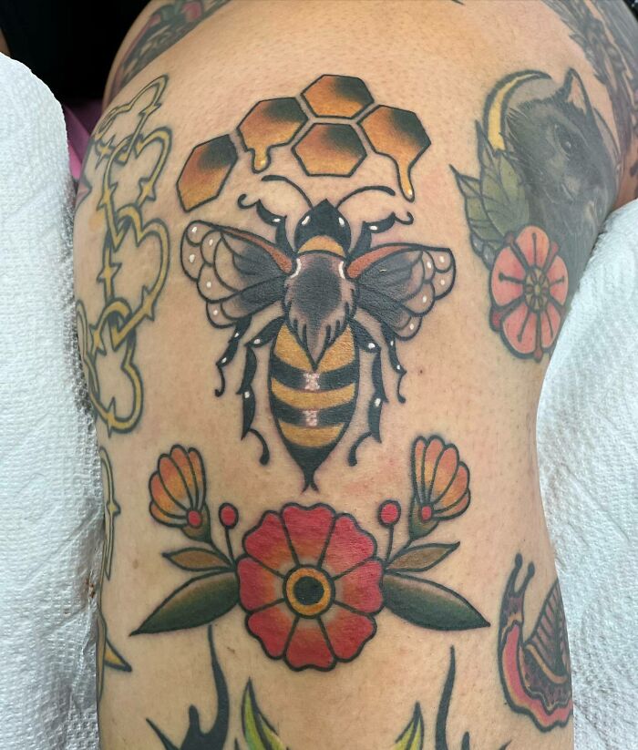 Bee and floral knee tattoos with honeycomb design.